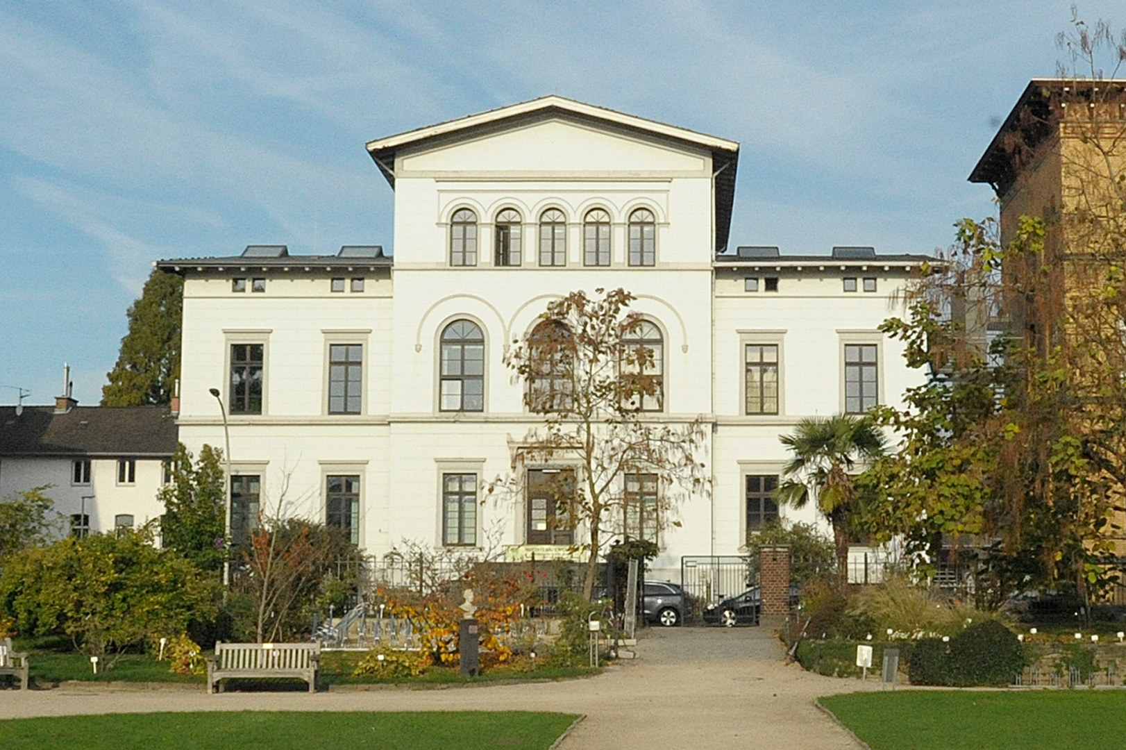 Eine Wissenschaftlerin und ein Wissenschaftler arbeiten hinter einer Glasfassade und mischen Chemikalien mit Großgeräten.