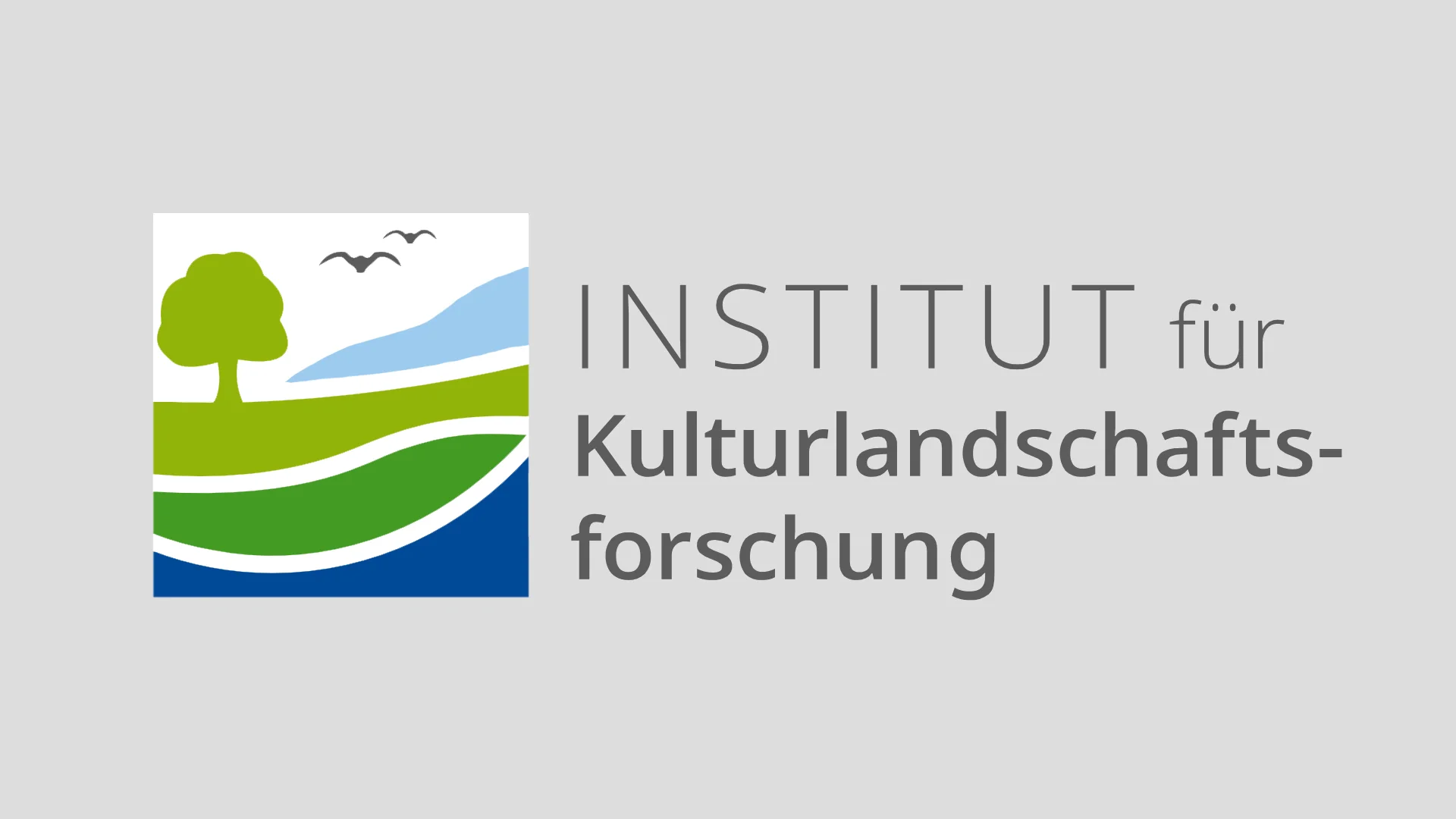 Eine Wissenschaftlerin und ein Wissenschaftler arbeiten hinter einer Glasfassade und mischen Chemikalien mit Großgeräten.